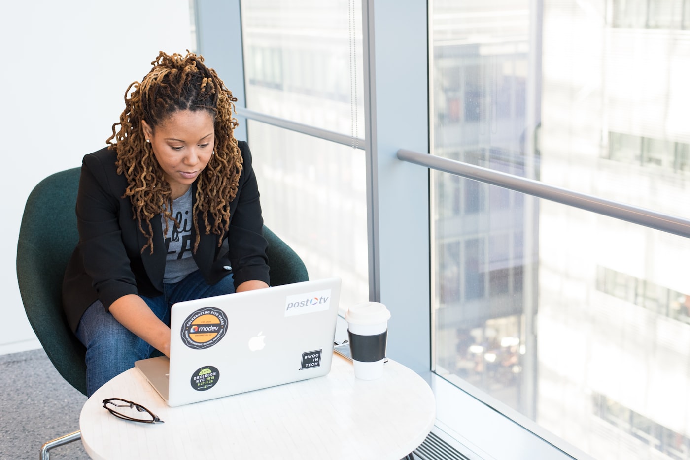 A woman completing an online assessment on her laptop beside a bright window