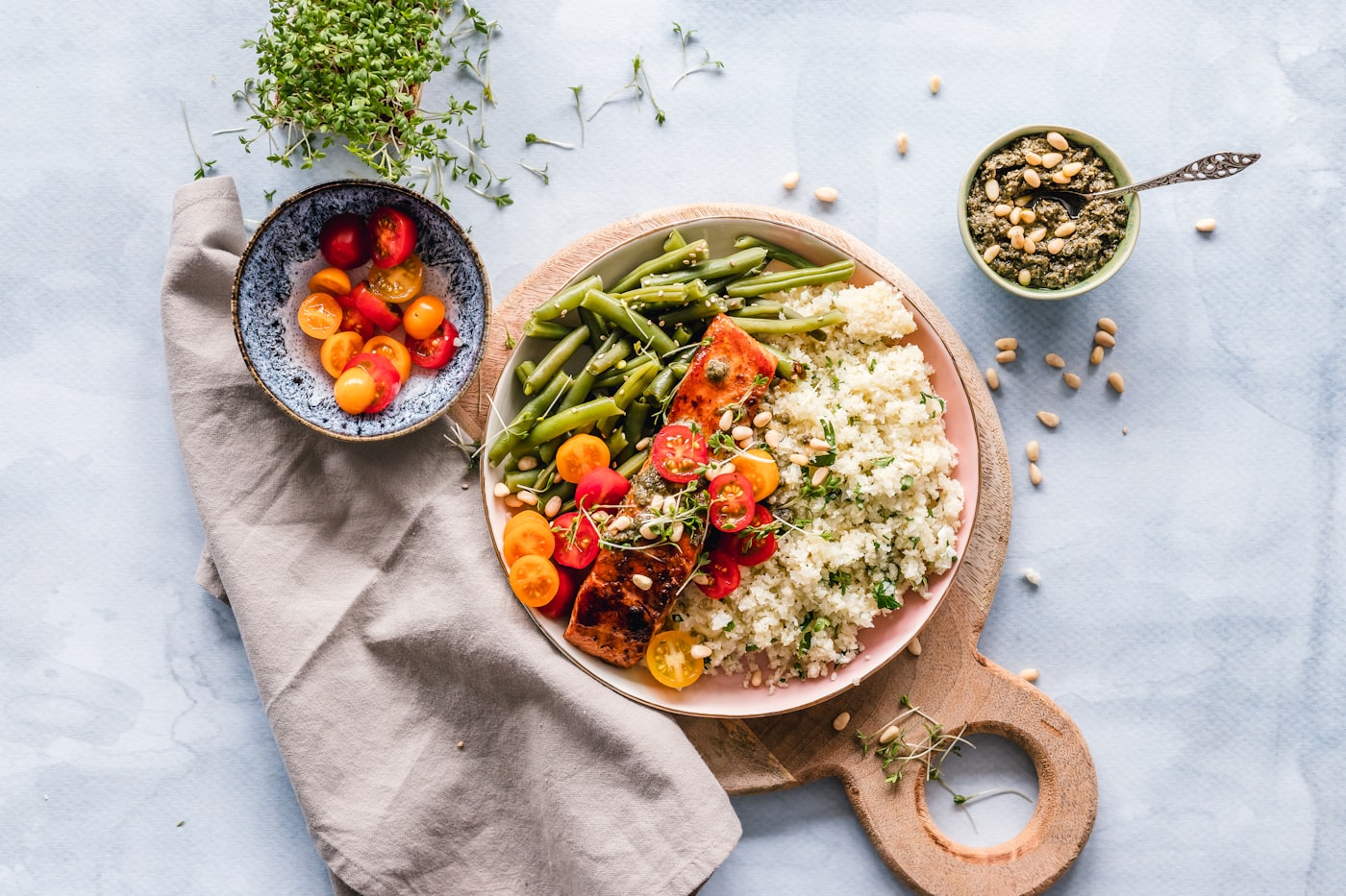 Overhead grain bowl with vegetables, tomatoes, and herbs on a linen napkin